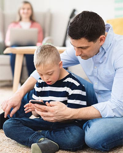 a male in blue with his kid having a online Telehealth consultation from their home